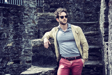 Attractive man outdoor in old European castle, in Switzerland. Athletic build, with tight t-shirt and sunglasses