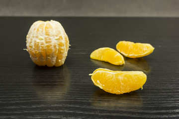 A part of an orange on a dark table.
