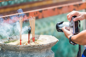 Hands holding a camera and taking a picture of chinese incense
