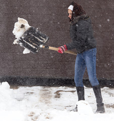 Girl with a shovel cleans the snow