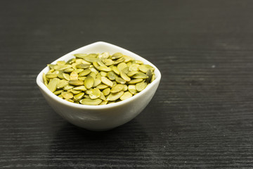A bowl with pumpkin seeds on the table.