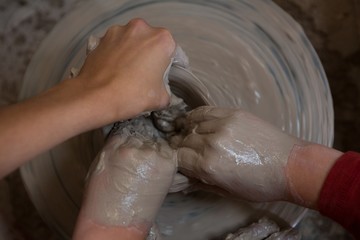 Fototapeta premium Female potter assisting boy in molding a clay