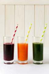 Detox drinks in glasses: fresh smoothies from vegetables: beet, carrot, spinach, cucumber and apple on white background