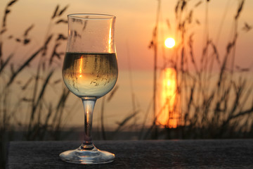 Weissweinglas vor Strand bei Sonnenuntergang mit dekorativen Gräsern.Where: Sylt, Wenningstedt, Rotes Kliff.When: 04.07.2015,