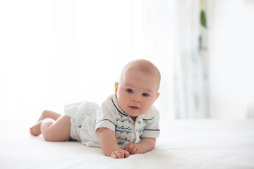 Fototapeta premium Cute little four month old baby boy, playing at home in bed