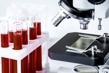 blood in glass tubes on background of microscope