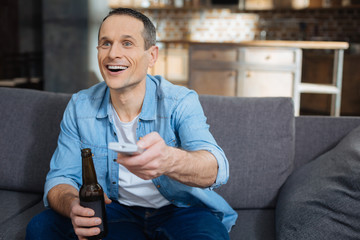 Watching movie. Handsome male opening mouth and laughing while watching program