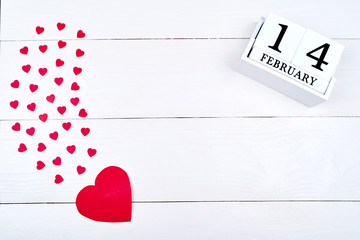 White wooden Valentines Day background with paper red hearts and wooden block calendar, copy space. Greeting card mockup for Saint Valentines Day. Symbol of love. Love concept, Top view, flat lay