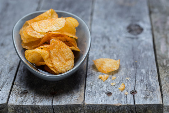 Kartoffelchips auf grauem rustikalen Holz