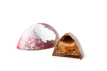 Cut handmade chocolate candy with caramel on white background