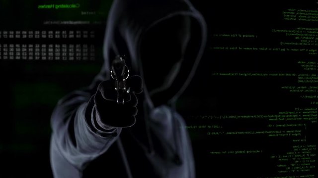Closeup of hooded male with gun in front of animated PC code, shooting in camera