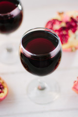 Organic pomegranate wine on white wooden table.
