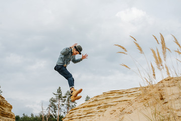 Hiker jumping over dunes. Sports life. Extreme man in hipster wear.