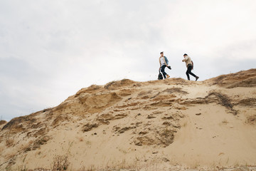 Adventurers standing on a desert mountain road and admires stunning dune range. Epic expedition in the forests Europe.