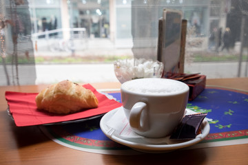A cup of aroma morning cappuccino with freshly baked croissant