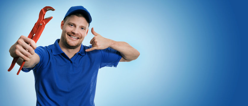 plumbing services - plumber with wrench showing phone call gesture on blue background with copy space