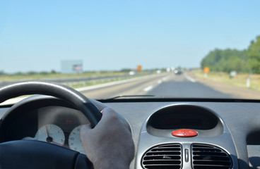 Naklejka premium Man driving a car on a highway with other vehicles blurred in front of him