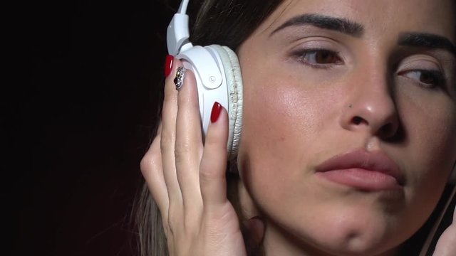 Pensive brunette with piercing in the nose listening to music on headphones