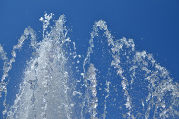 Top of fountain water and its spray against clear blue sky