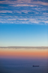 Beautiful sunrise over the sea and sailing cargo ship