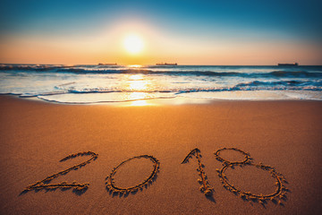 Happy New Year 2018 concept, lettering on the beach. Sea sunrise
