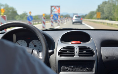 Driving a car on a highway with roadworks and with other vehicles blurred in front of him
