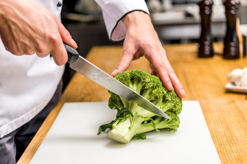 cropped image of chef cutting broccoli