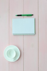 Open notebook with green pen and coffee cup