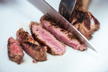 cropped image of chef cutting fried meat with knife and fork