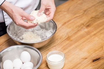 cropped image of chef preparing dough on wooden table