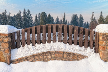 Fototapeta premium fence in snow closeup and a view of the forewooden fence in snow and forest viewsst