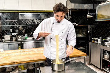chef taking pasta with fork from pot