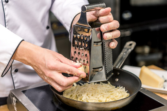 cropped image of chef grating cheese on grater