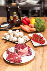 raw meat and uncooked vegetables on wooden table