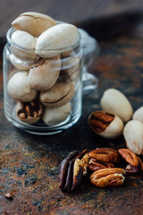Pecan nuts inside glass jar on rustic surface.