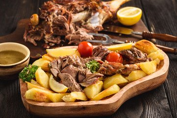 Slow baked lamb leg with potatoes and sauce.