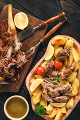 Slow baked lamb leg with potatoes and sauce.