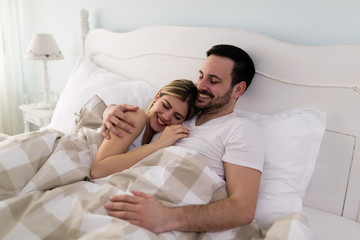 Young attractive couple having romantic time in bed