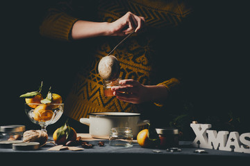Female hands pouring orange jam into glass jars for Christmas gifts