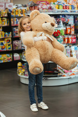 Happy little girl holding big teddy bear