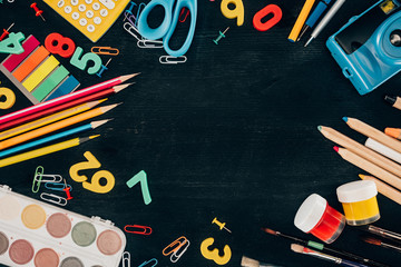 Top view of composition of colorful school supplies isolated on dark board background