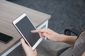 Mid section of female executive using digital tablet at table