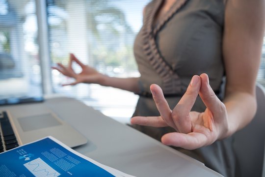 Mid Section Of Female Executive Performing Yoga At Desk