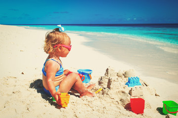 cute little girl play with sand on beach