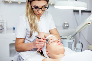 Cosmetologist is doing procedure for young girl. Procedure of Microdermabrasion. Model, close-up. Cosmetological clinic. Healthcare