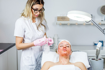 Cosmetologist is doing Face peeling mask, spa beauty treatment for young girl. Model, close-up. Cosmetological clinic. Healthcare