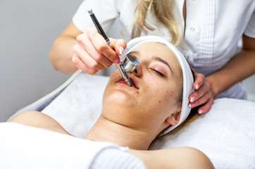 Naklejka premium Cosmetologist is doing procedure for young girl. Procedure of Microdermabrasion. Model, close-up. Cosmetological clinic. Healthcare 