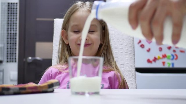 Child girl drinking milk at the kitchen