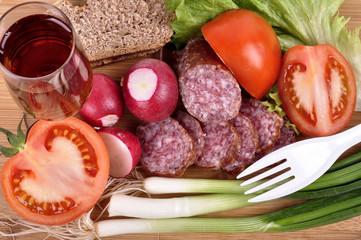 radish, onion, tomato, sausage, wine in a glass on a wooden background