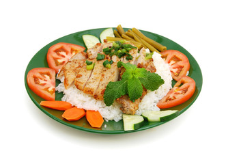 A baked pork chop with rice and cucumber, tomatoe